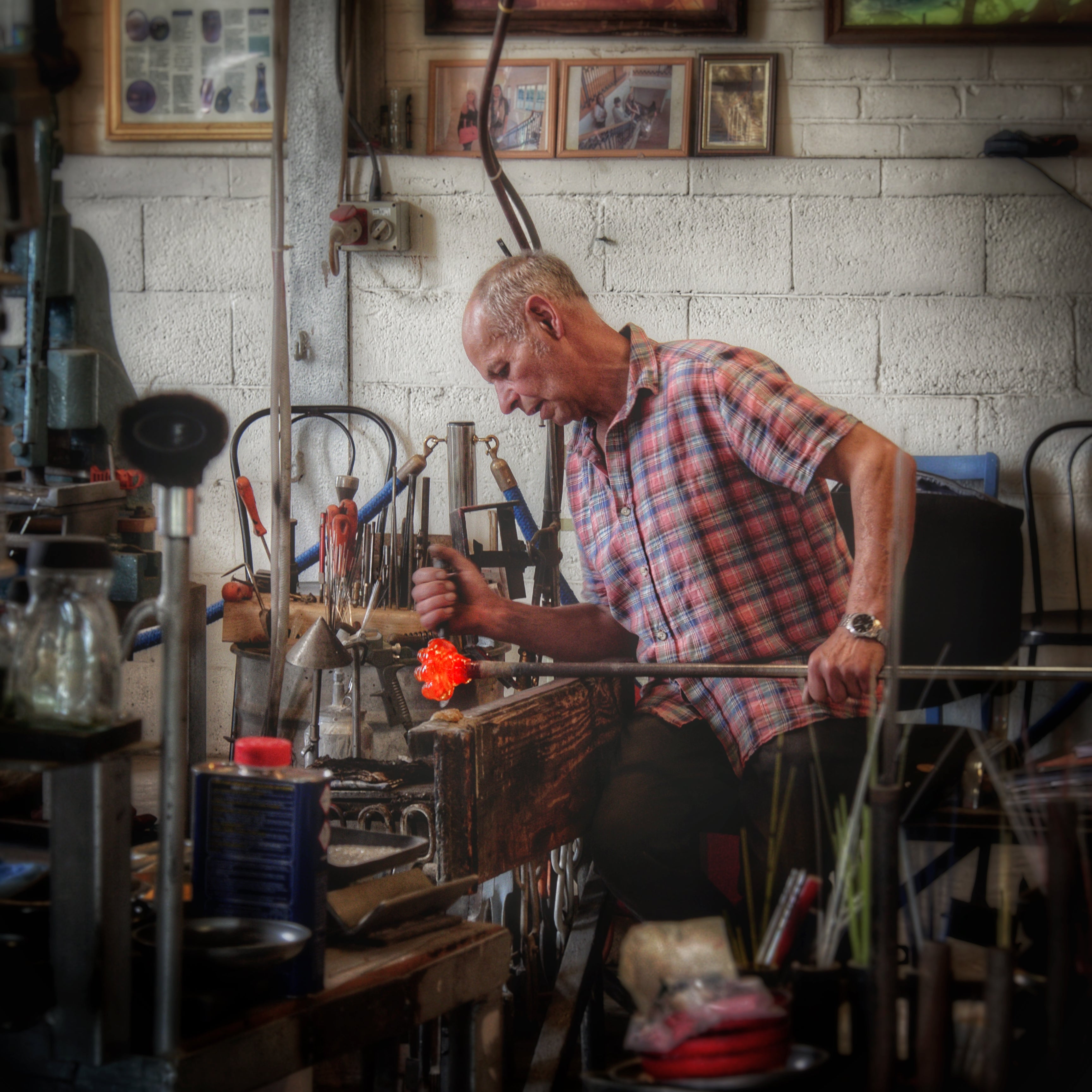 John  using tools to shape and mould the hot glass, transforming it from a molten mass to a three dimension form.