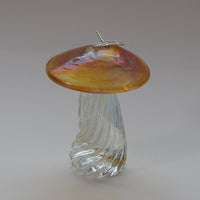 silver dragonfly resting on an iridescent gold capped handmade glass toadstool
