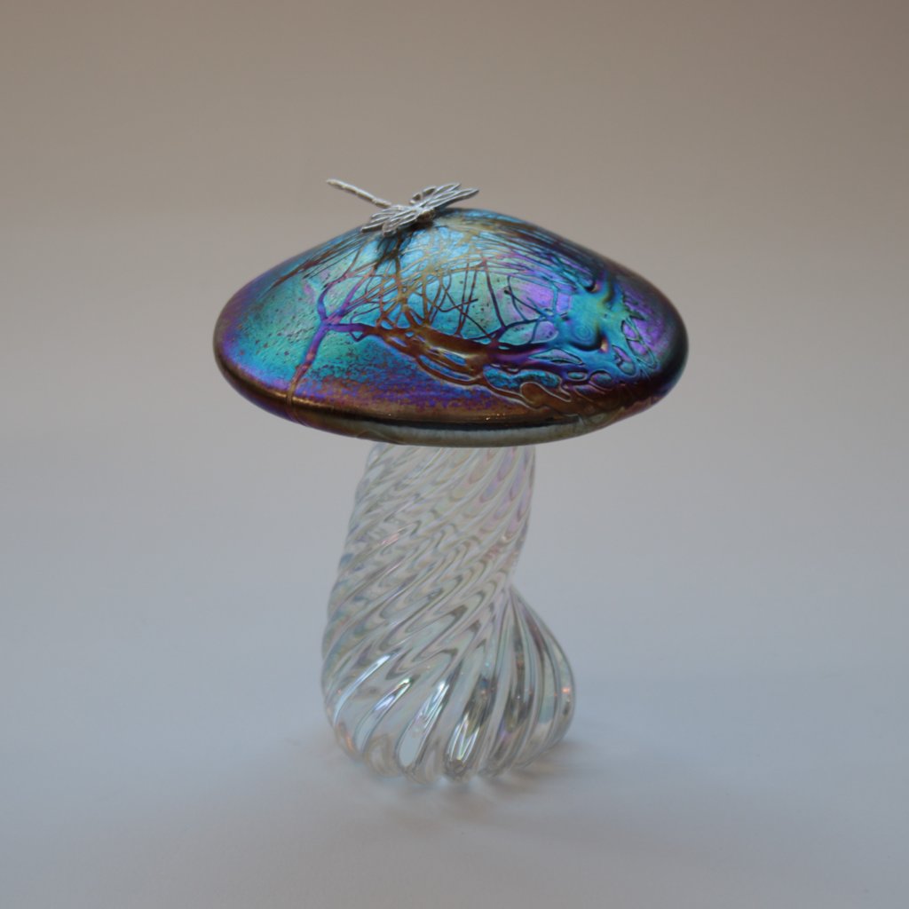 silver dragonfly resting on an iridescent capped handmade glass toadstool