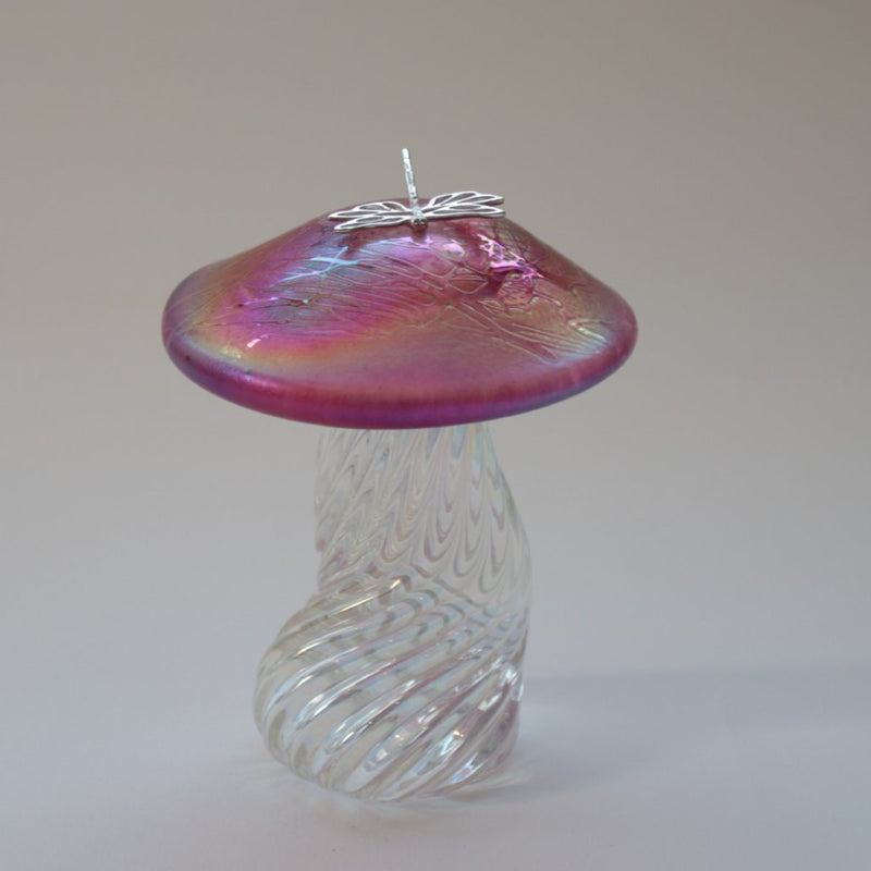 silver dragonfly resting on an iridescent pink capped handmade glass toadstool