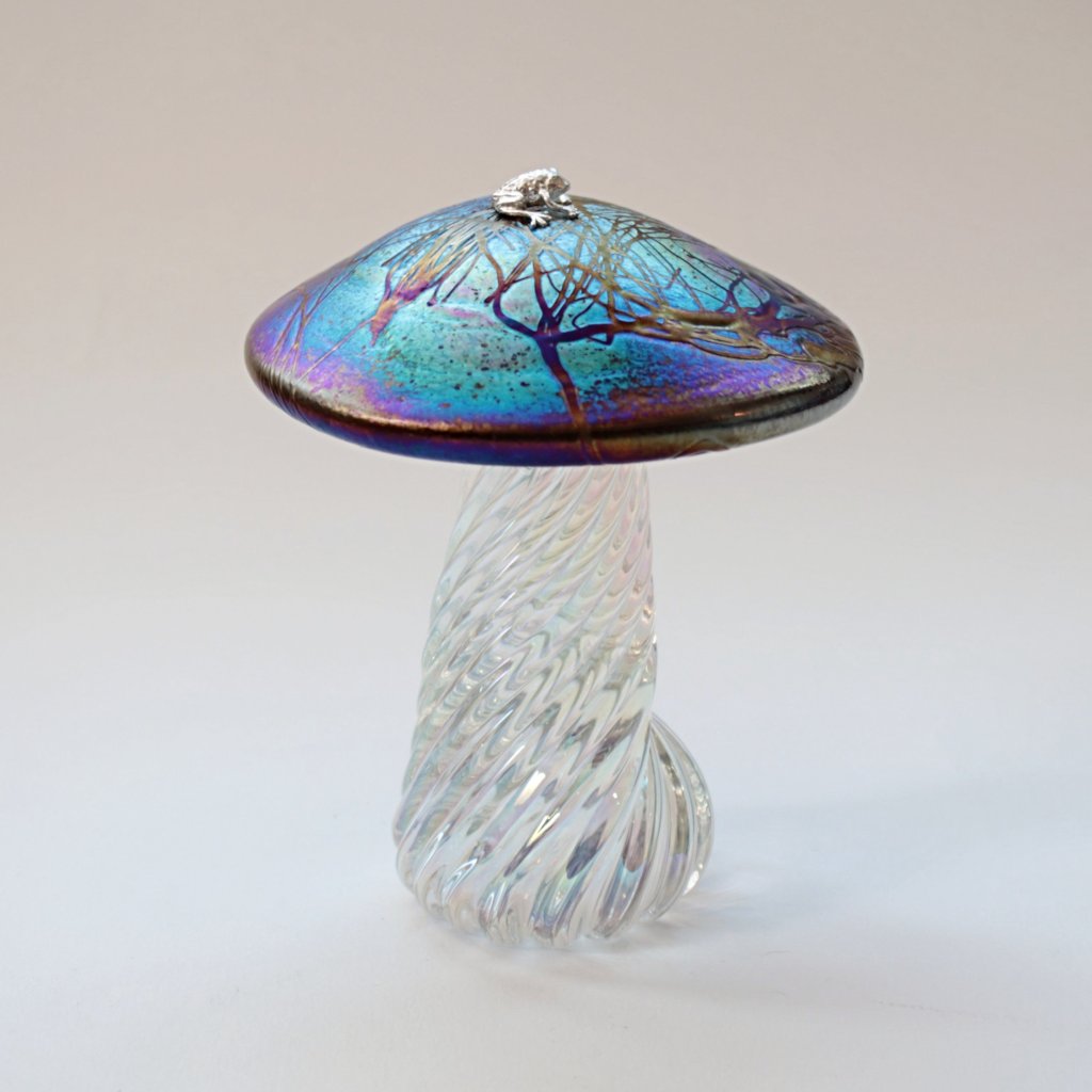 silver frog sitting on an iridescent handmade glass toadstool